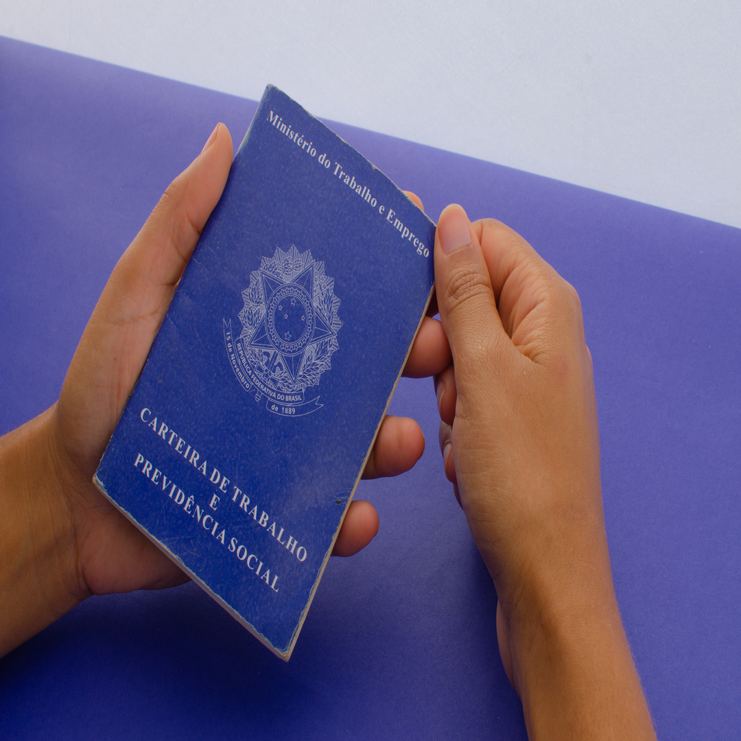 Brazil Work Card. Translation - Federative Republic of Brazil, Ministry of Labor. Hand holding the Brazil Work Card. Labor document FGTS, INSS, unemployment, salary, CTPS and CLT.